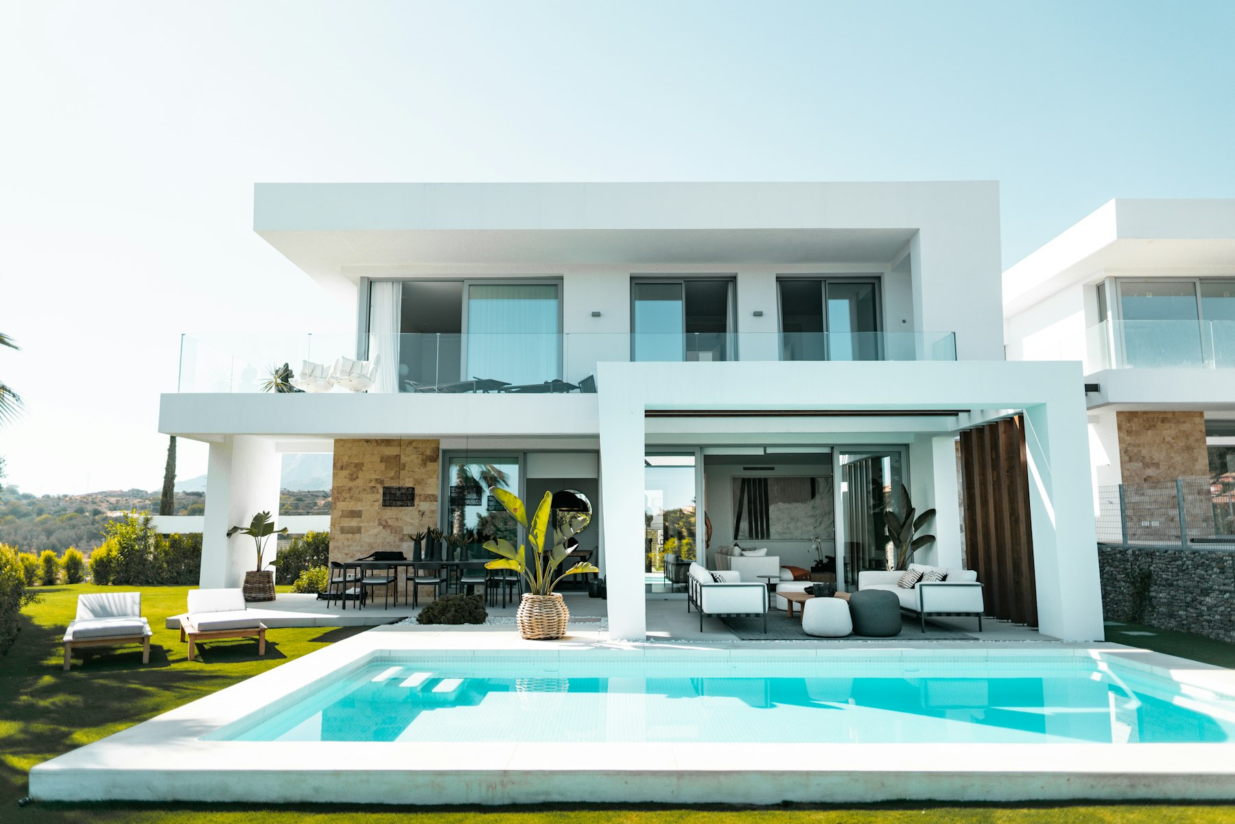 Casa de arquitectura contemporánea con terraza, jardín y piscina en un conjunto residencial.